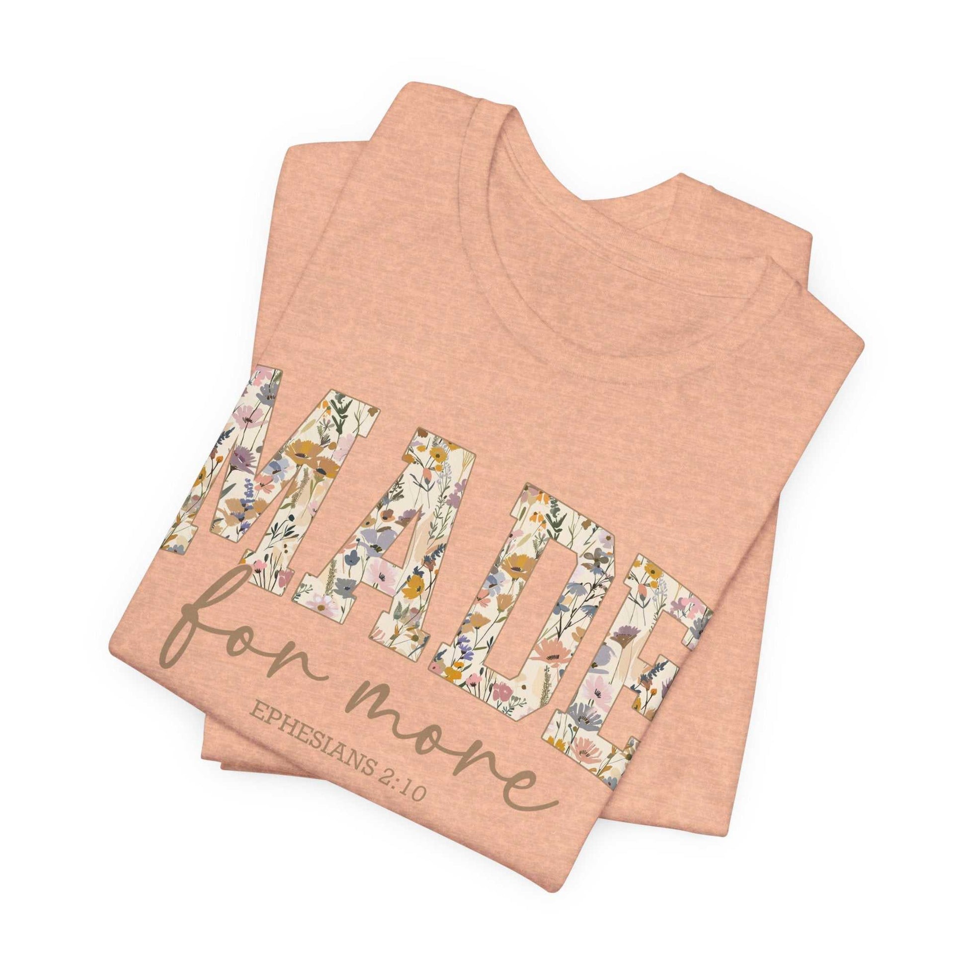 Folded peach Made for More Tee with floral patterned text and scripture reference Ephesians 2:10