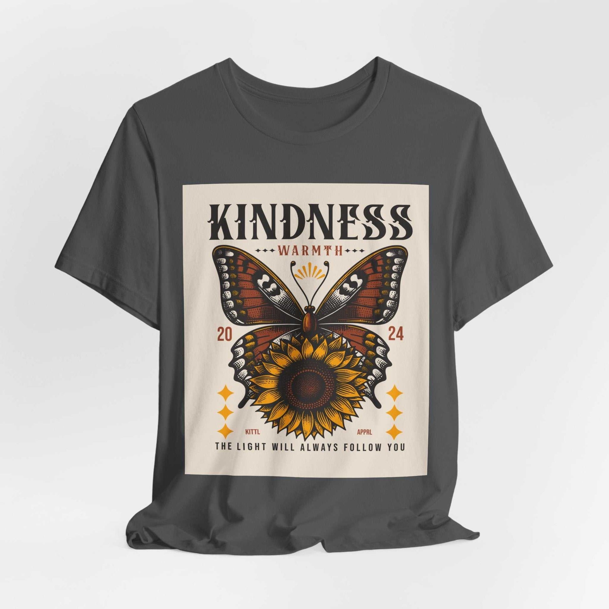 Dark gray Kindness Butterfly Tee featuring a butterfly and sunflower graphic with the text "KINDNESS WARMTH 2024" and "THE LIGHT WILL ALWAYS FOLLOW YOU" on the front