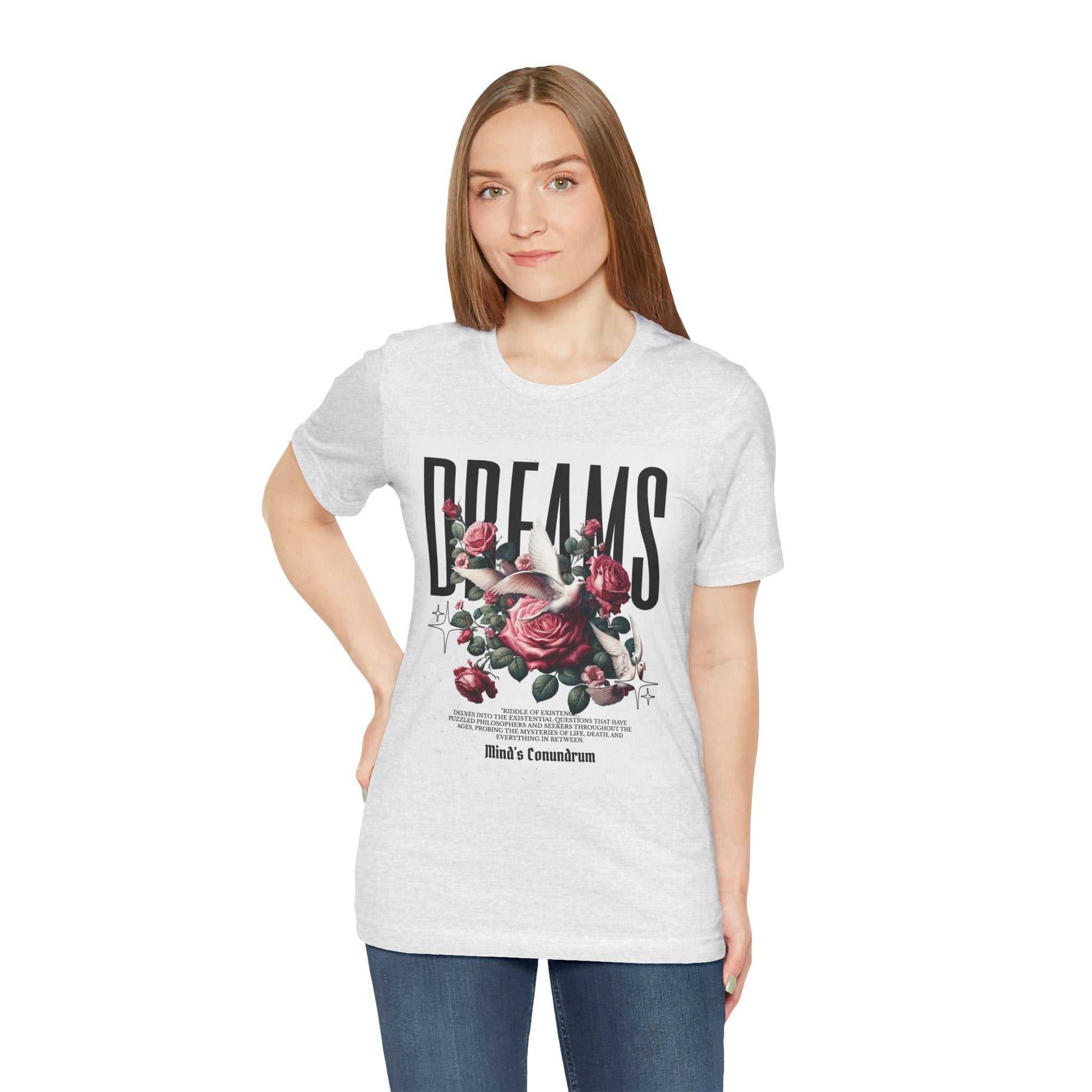 Woman wearing a white Dreams Floral Tee with bold black text and pink rose graphic, paired with blue jeans.