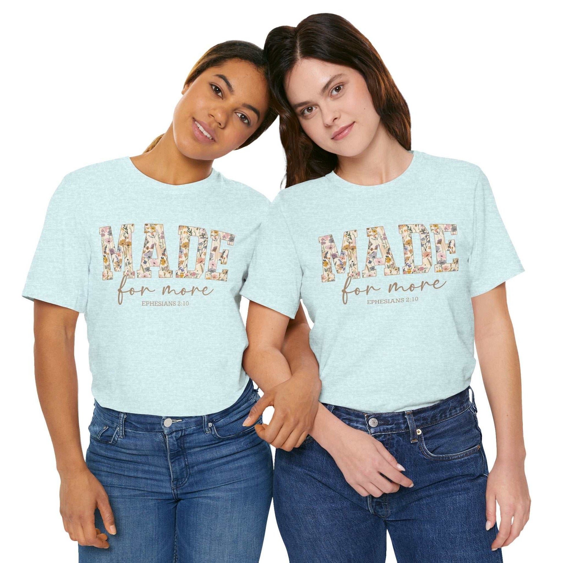 Two women wearing light blue "Made for More" unisex jersey short sleeve tees with floral design and scripture text, styled casually with jeans.