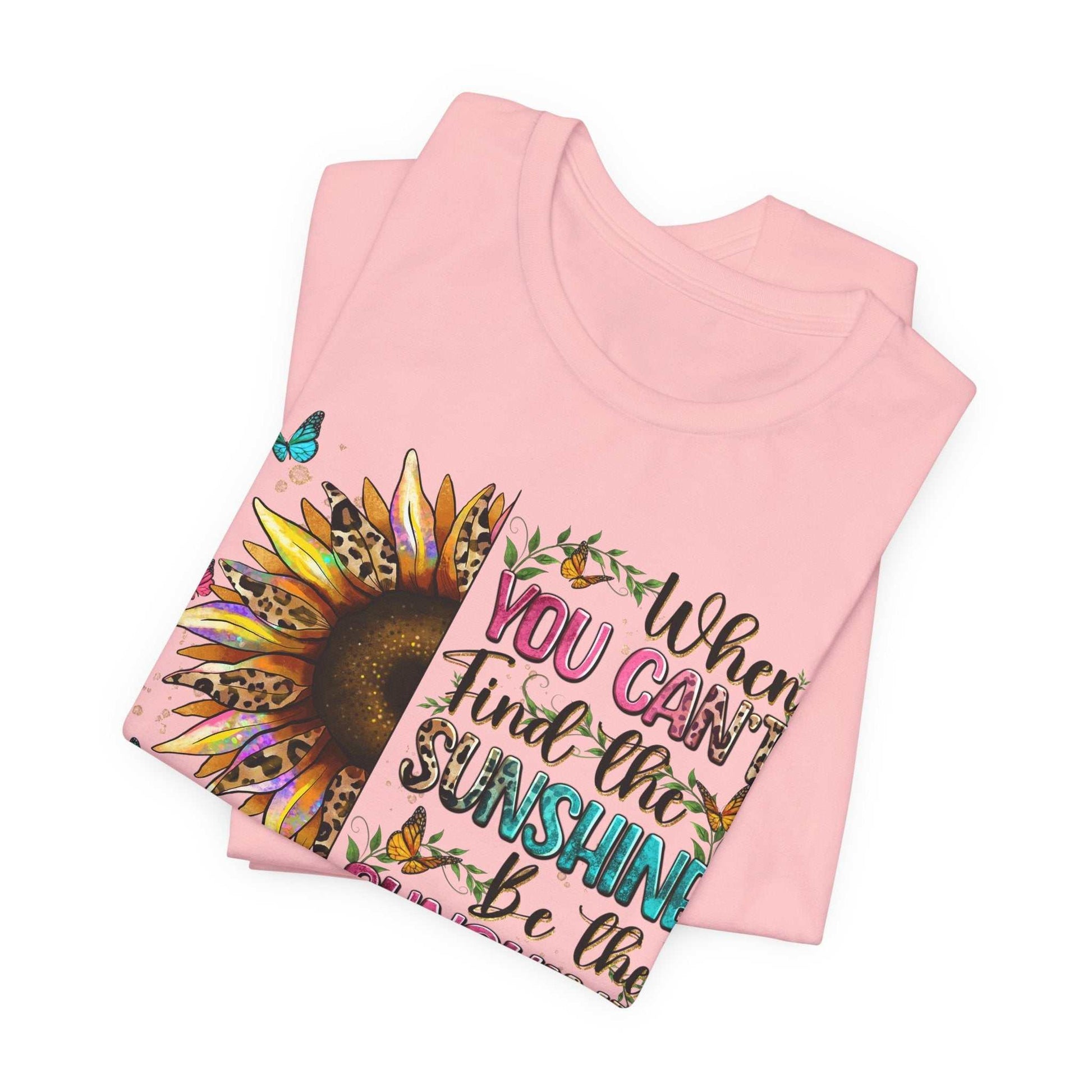 Folded pink Sunshine Quote Tee with sunflower and colorful text design on front