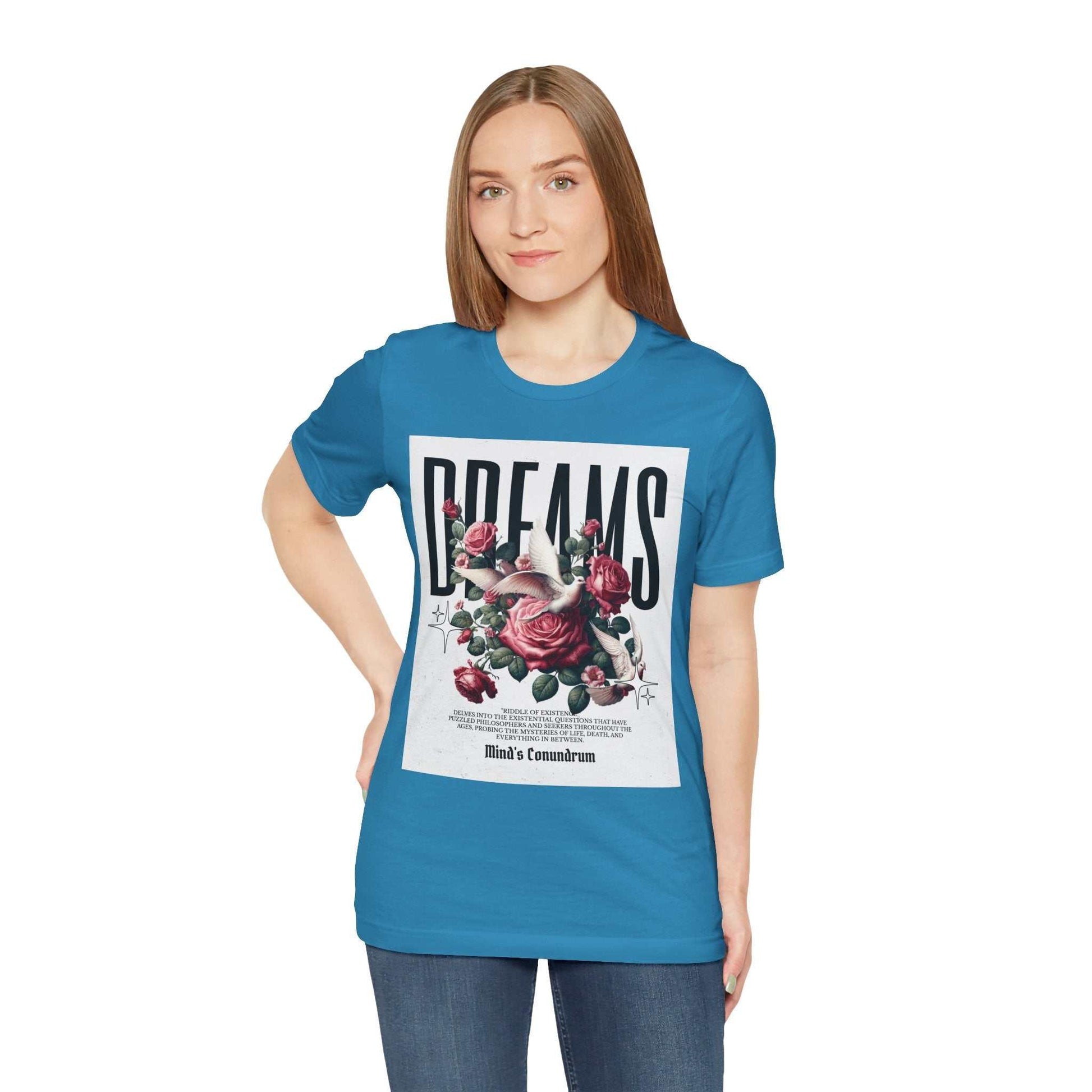 Woman wearing a blue Dreams Floral Tee with a large floral and typography design on the front, paired with jeans