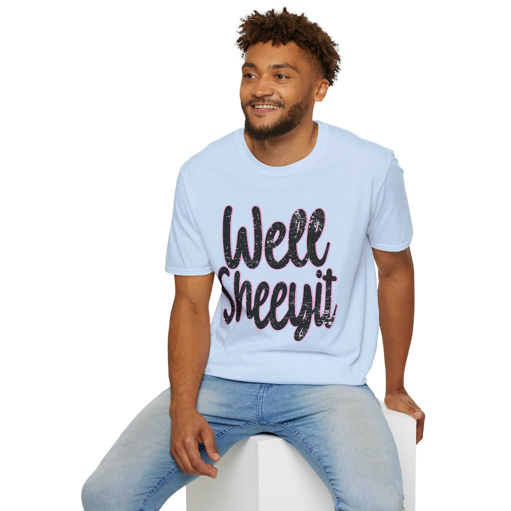 Man wearing light blue casual statement tee with "Well Sheeyit" funny quote sitting on white block
