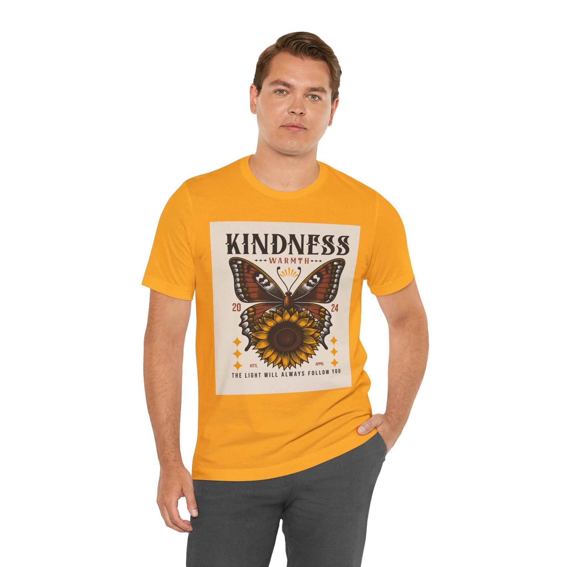 Man wearing a yellow Kindness Butterfly Tee with a butterfly and sunflower graphic and the text "Kindness Warmth" on the front