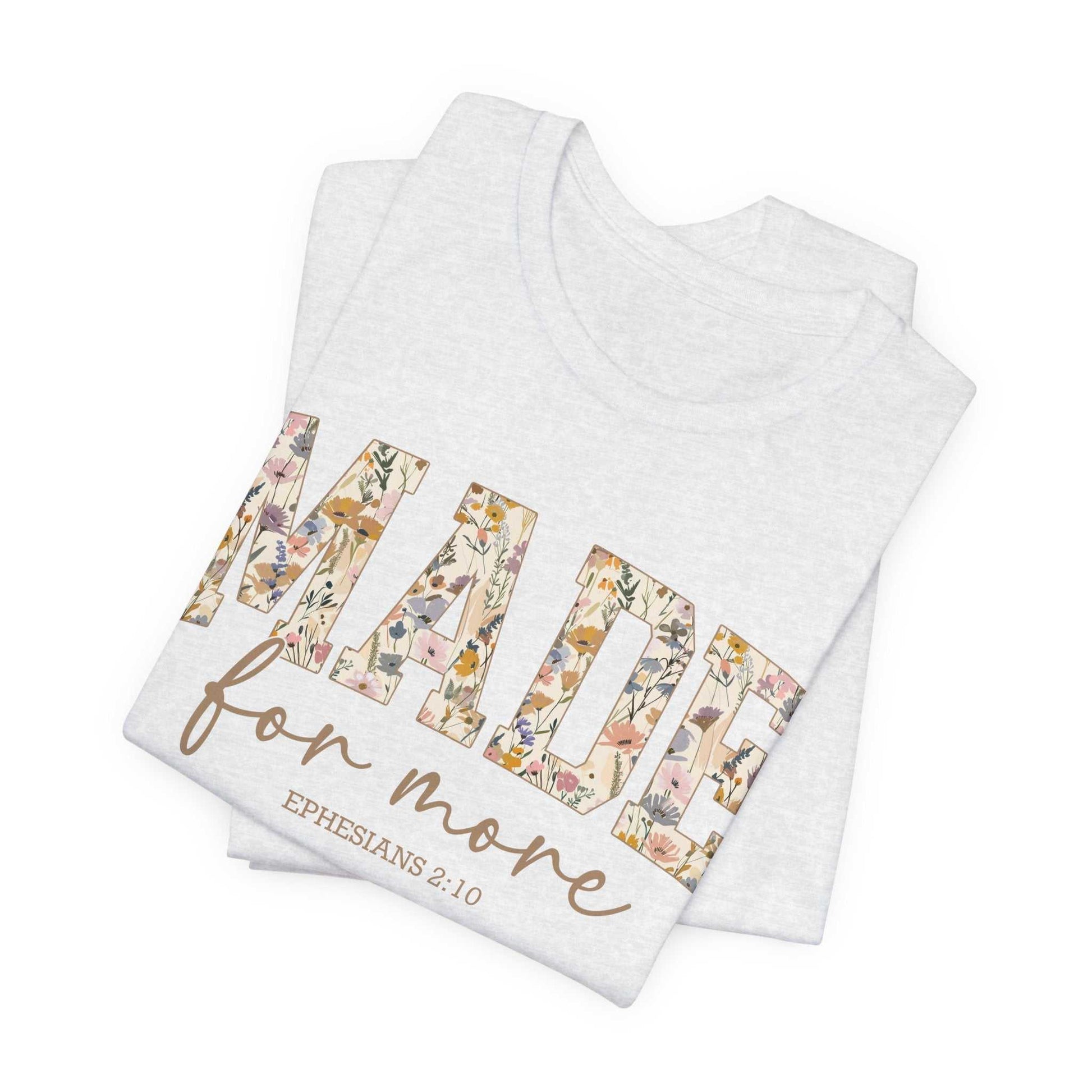 Folded white unisex jersey short sleeve tee with "MADE for more" floral text and Ephesians 2:10 scripture design
