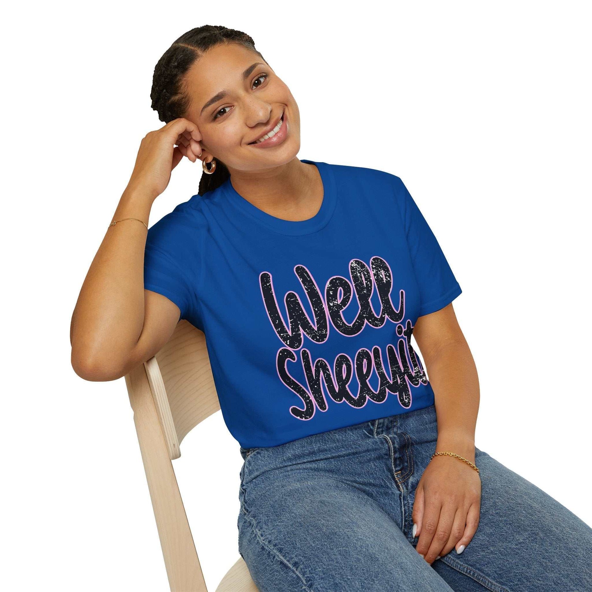 Woman wearing a blue casual statement tee with "Well Sheeyit" funny quote, paired with jeans sitting on a chair