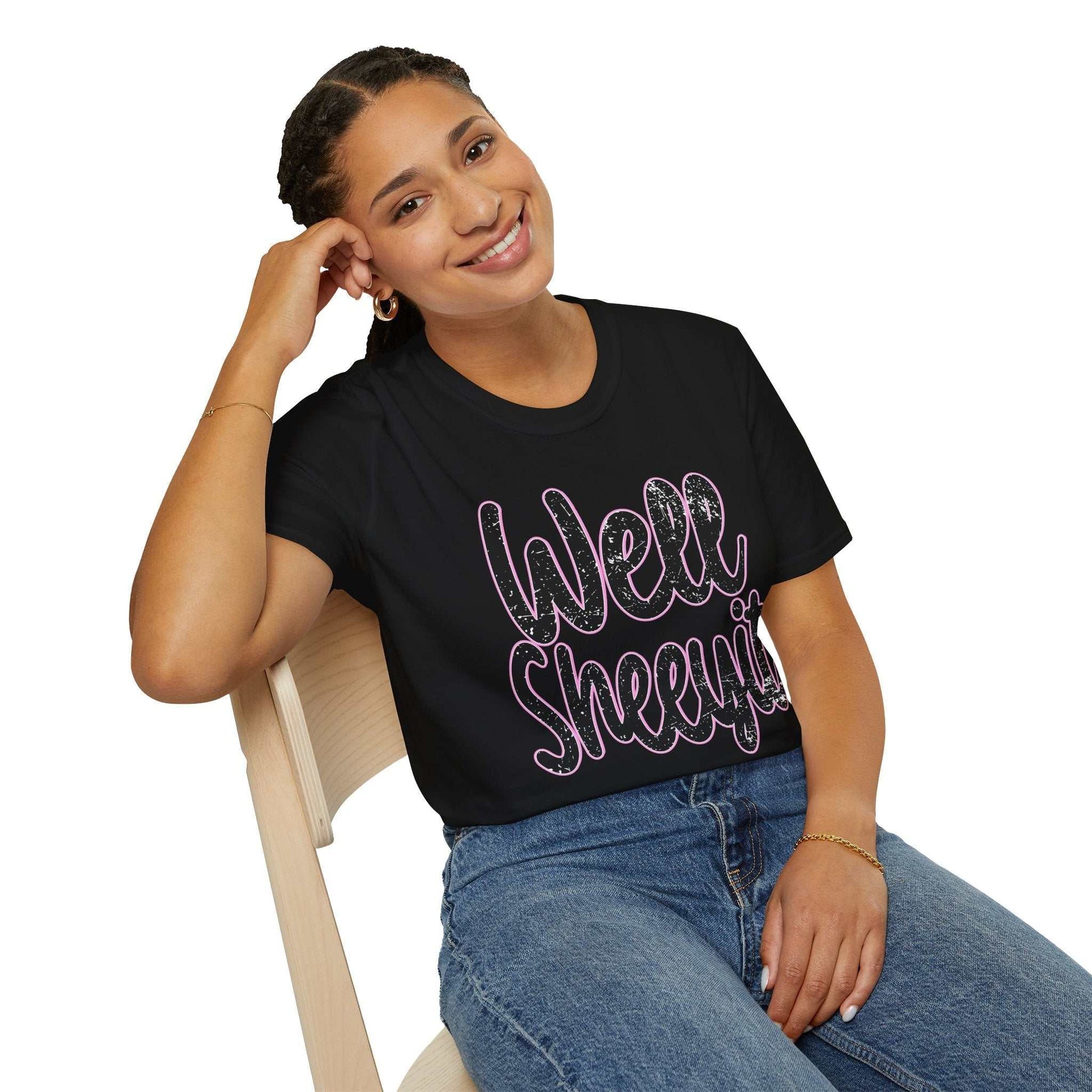 Woman wearing black casual statement tee with "Well Sheeyit" funny quote sitting on wooden chair